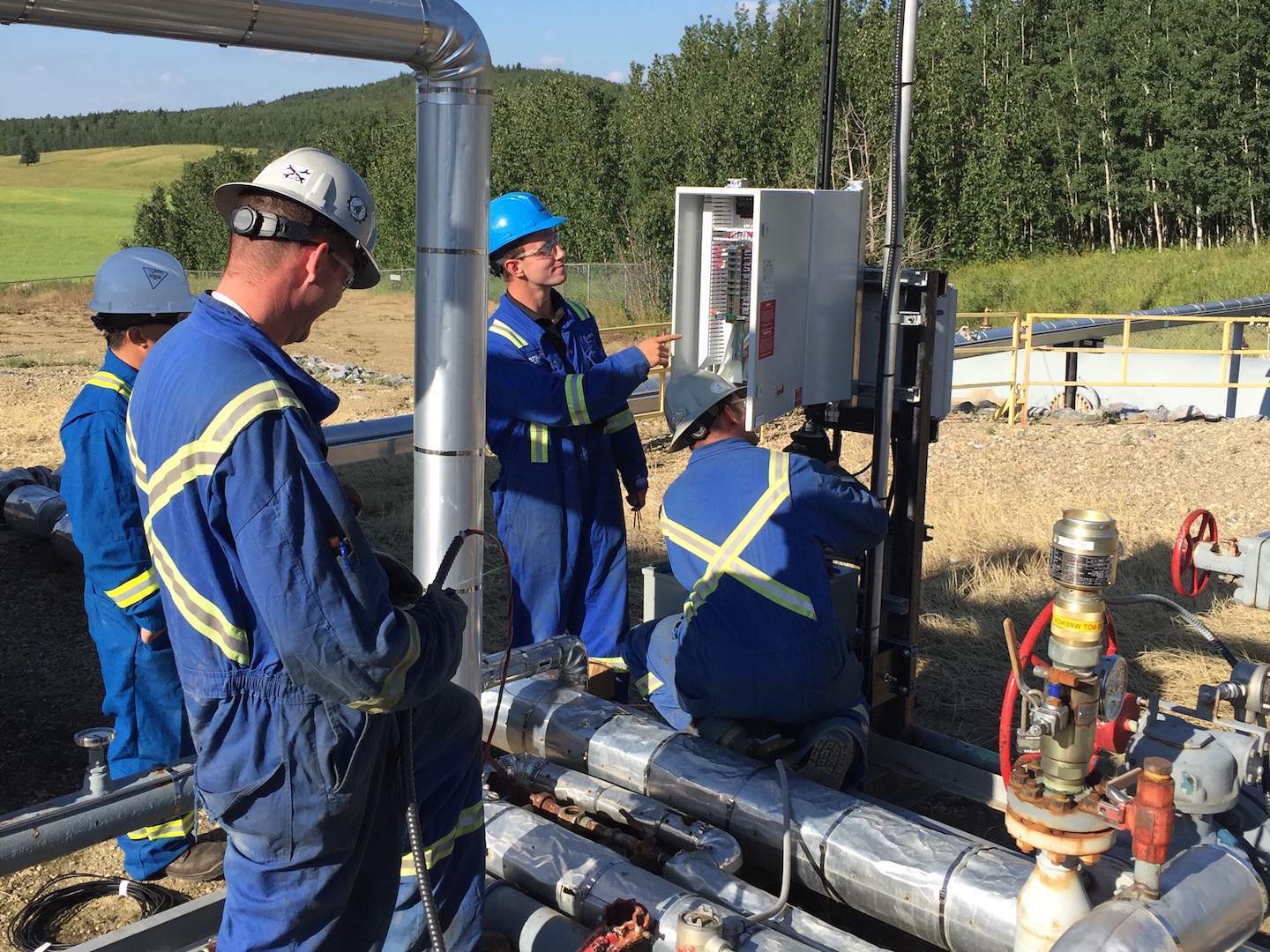 Four technicians working on installation of the CROSSFIRE ultra-low power solar chemical injection pump in the field